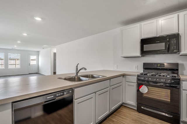 kitchen with sink, light hardwood / wood-style flooring, black appliances, white cabinets, and kitchen peninsula