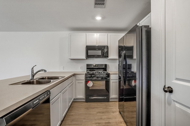 kitchen with white cabinetry, sink, and black appliances