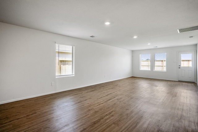 spare room with a healthy amount of sunlight and dark hardwood / wood-style floors