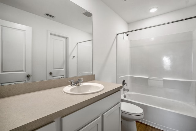 full bathroom featuring hardwood / wood-style flooring, washtub / shower combination, vanity, and toilet