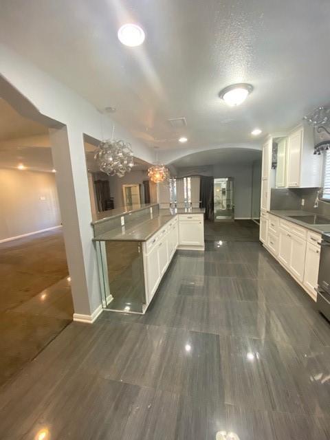 kitchen featuring pendant lighting, sink, white cabinetry, and kitchen peninsula