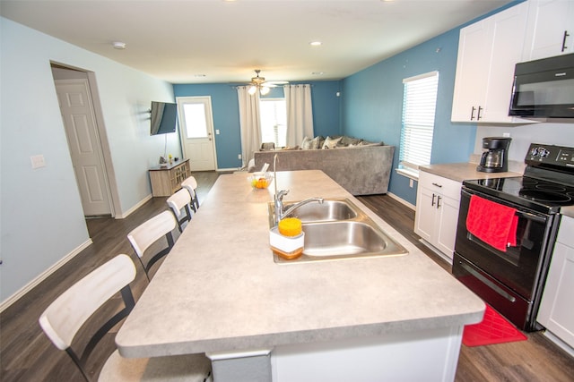 kitchen featuring white cabinets, an island with sink, and black appliances