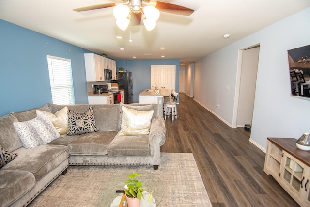 living room featuring ceiling fan and dark hardwood / wood-style flooring