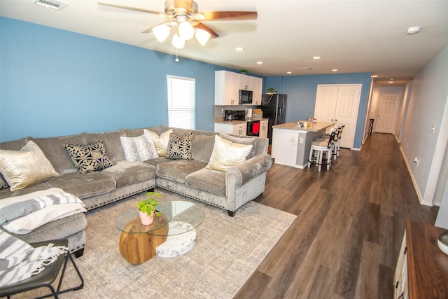 living room featuring dark wood-type flooring and ceiling fan