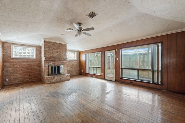 unfurnished living room featuring ornamental molding, hardwood / wood-style floors, a textured ceiling, and a fireplace