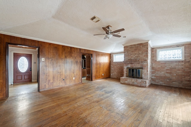 unfurnished living room with a brick fireplace, a wealth of natural light, and light hardwood / wood-style flooring