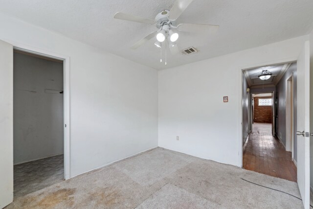 spare room featuring ceiling fan, light colored carpet, and a textured ceiling