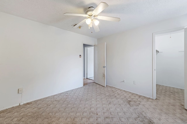 unfurnished room featuring ceiling fan, light colored carpet, and a textured ceiling