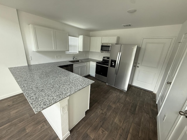 kitchen with dark hardwood / wood-style floors, white cabinetry, kitchen peninsula, stainless steel appliances, and light stone countertops