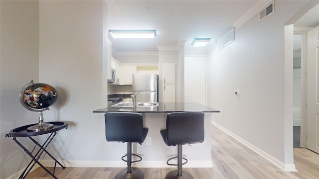 kitchen with crown molding, white cabinetry, a kitchen breakfast bar, stainless steel appliances, and kitchen peninsula