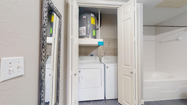 washroom with washing machine and clothes dryer, dark hardwood / wood-style floors, and water heater