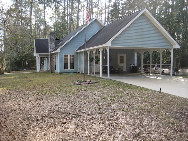 back of house with a carport and a yard