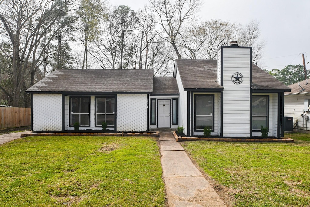 view of front of home with a front lawn, a chimney, central AC unit, and fence