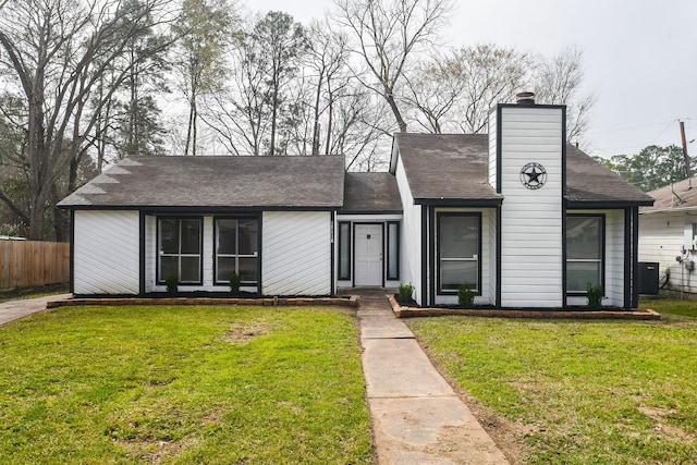 view of front of home with a front lawn, a chimney, central AC unit, and fence