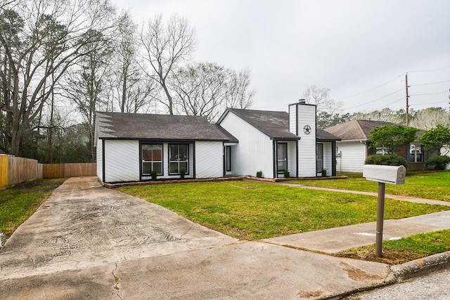 view of front of home featuring a chimney, fence, and a front yard