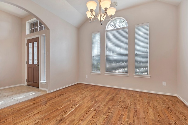 spare room featuring lofted ceiling, a chandelier, and light hardwood / wood-style flooring