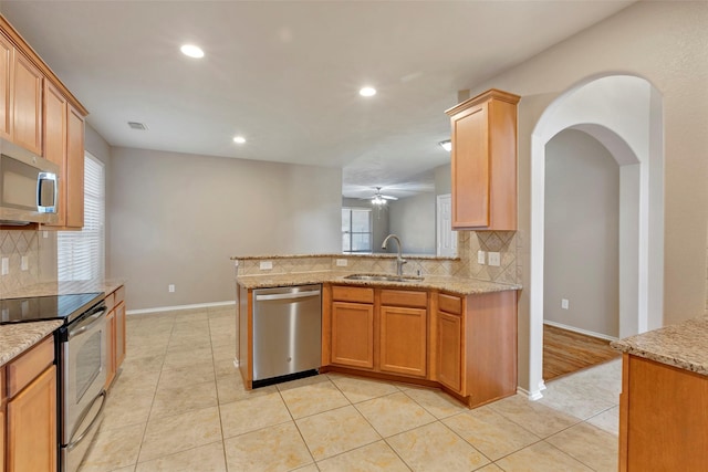 kitchen with sink, light tile patterned floors, stainless steel appliances, and light stone countertops