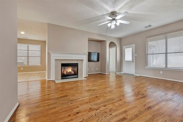 unfurnished living room featuring light hardwood / wood-style flooring, a tile fireplace, and ceiling fan