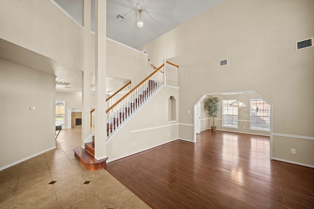 interior space with a tiled fireplace, hardwood / wood-style floors, a towering ceiling, and an inviting chandelier