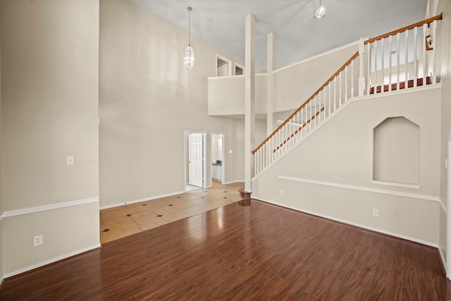 unfurnished living room featuring hardwood / wood-style floors and a towering ceiling