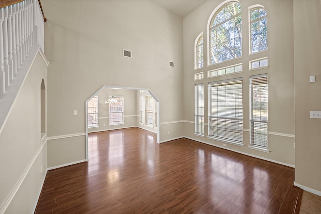 unfurnished living room with dark wood-type flooring and an inviting chandelier