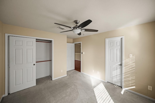 unfurnished bedroom with light colored carpet, a closet, and ceiling fan