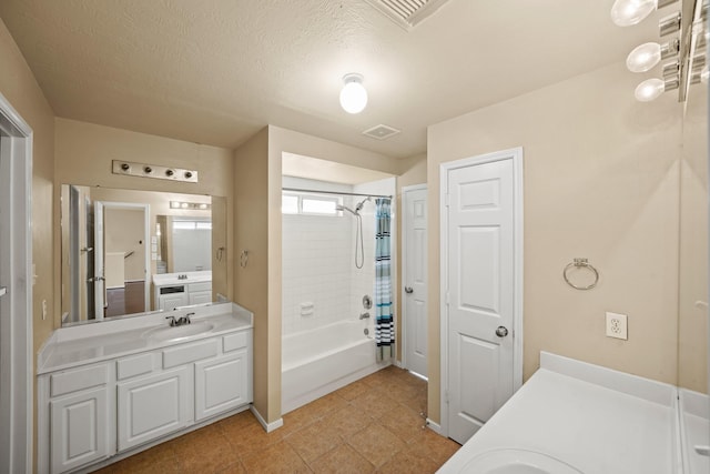 bathroom featuring vanity, a textured ceiling, tile patterned floors, and tiled shower / bath