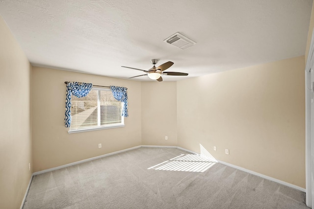 empty room featuring ceiling fan, light carpet, and a textured ceiling