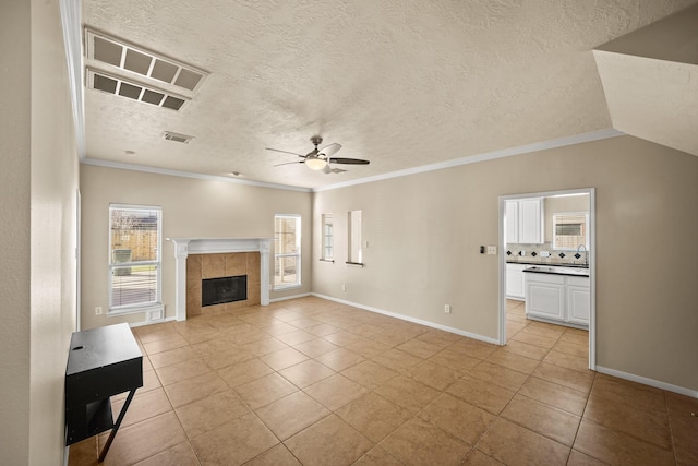 unfurnished living room with ornamental molding, light tile patterned floors, ceiling fan, and a fireplace