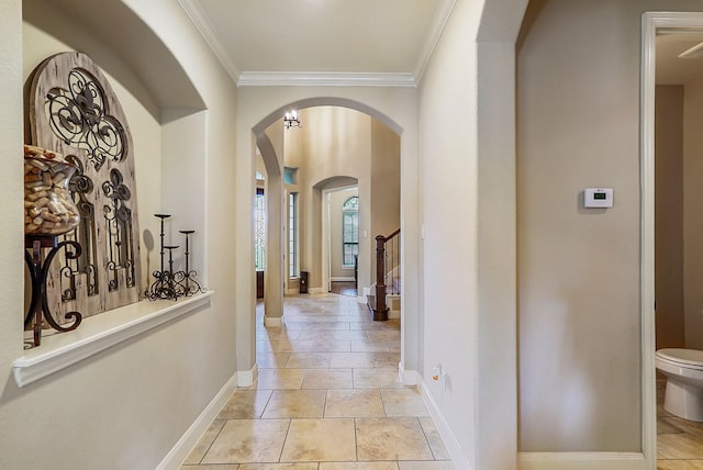 hallway with arched walkways, crown molding, stairway, and baseboards