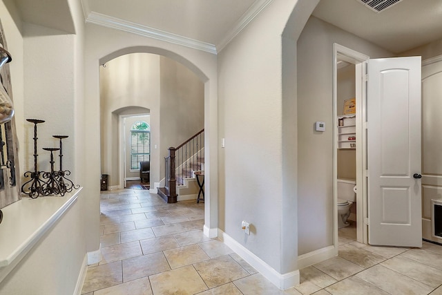 interior space featuring arched walkways, ornamental molding, visible vents, and baseboards