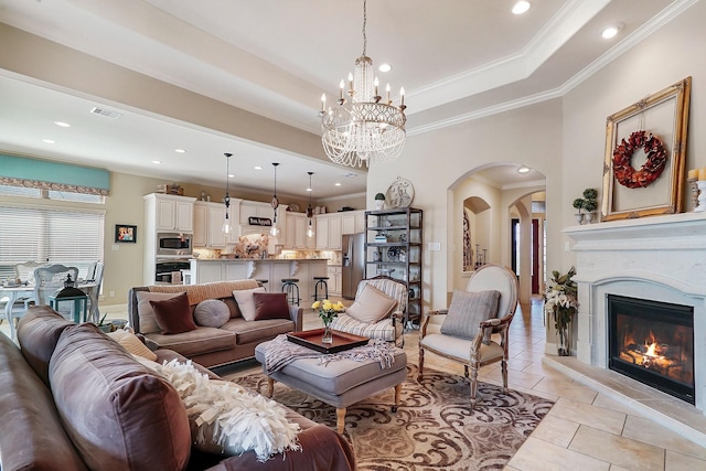 living area with arched walkways, visible vents, ornamental molding, a tray ceiling, and a glass covered fireplace