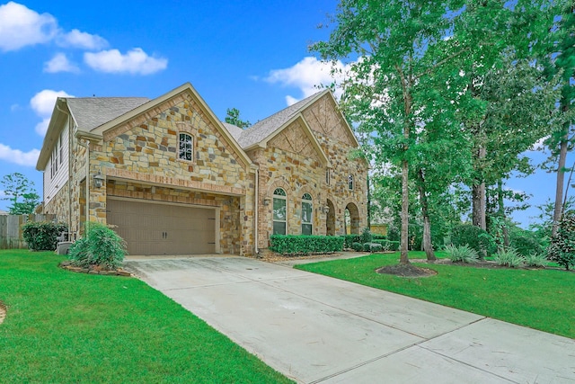 view of front of home with stone siding, concrete driveway, and a front yard