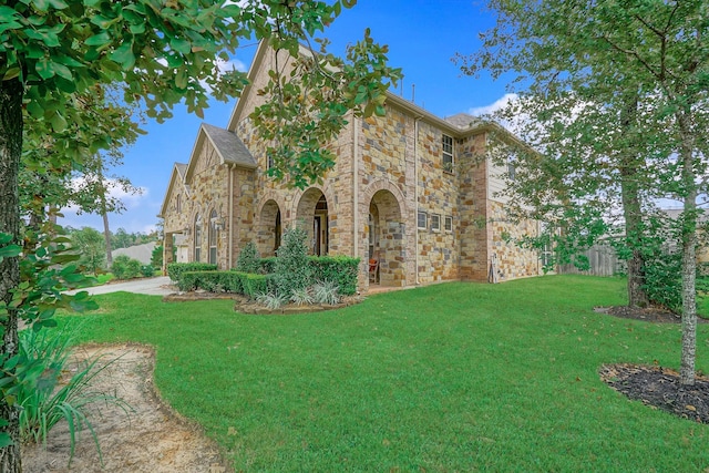 view of front facade with stone siding and a yard