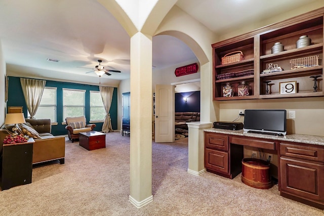 office space with light colored carpet, visible vents, a ceiling fan, built in study area, and baseboards