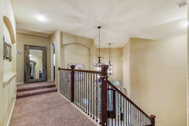 hall featuring light carpet, attic access, baseboards, visible vents, and an upstairs landing