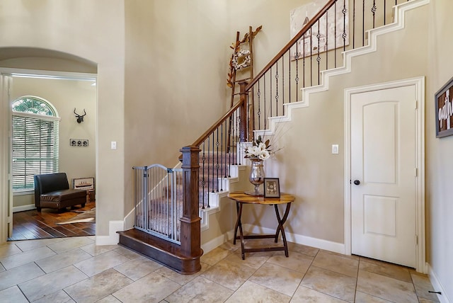 foyer with light tile patterned flooring, a towering ceiling, and baseboards