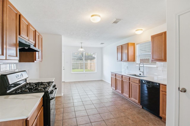 kitchen featuring pendant lighting, sink, stainless steel gas stove, black dishwasher, and decorative backsplash