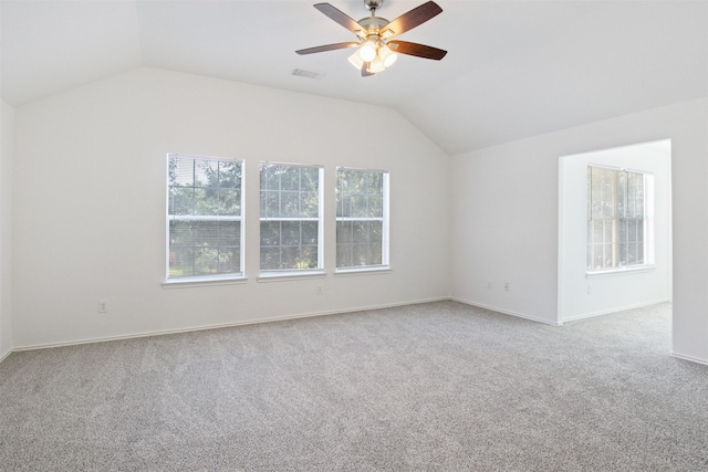 carpeted empty room with vaulted ceiling, a healthy amount of sunlight, and ceiling fan