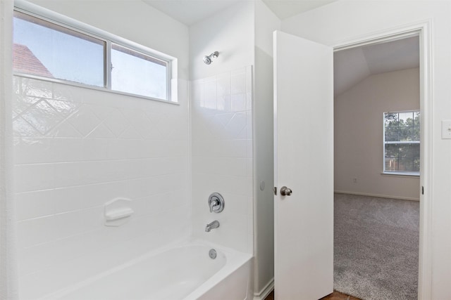 bathroom featuring lofted ceiling, tiled shower / bath combo, and a wealth of natural light