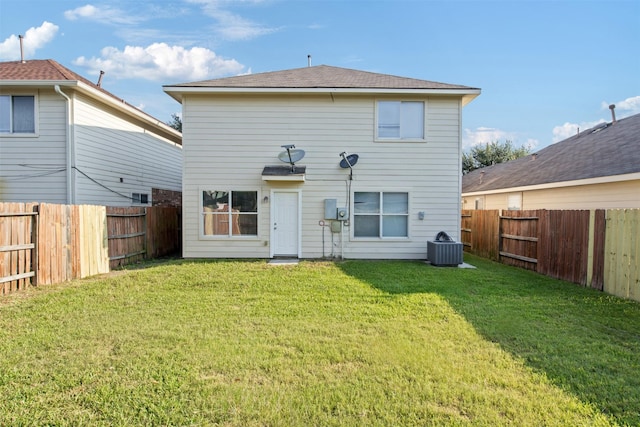 rear view of house with central AC unit and a lawn