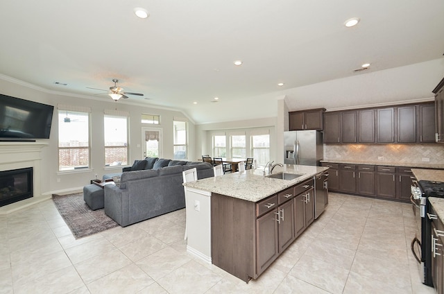 kitchen with sink, dark brown cabinets, stainless steel appliances, an island with sink, and decorative backsplash
