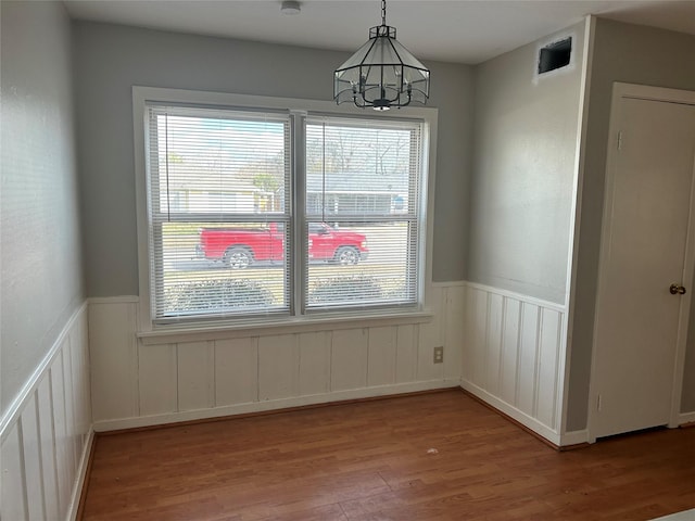 unfurnished dining area featuring a chandelier and light hardwood / wood-style floors