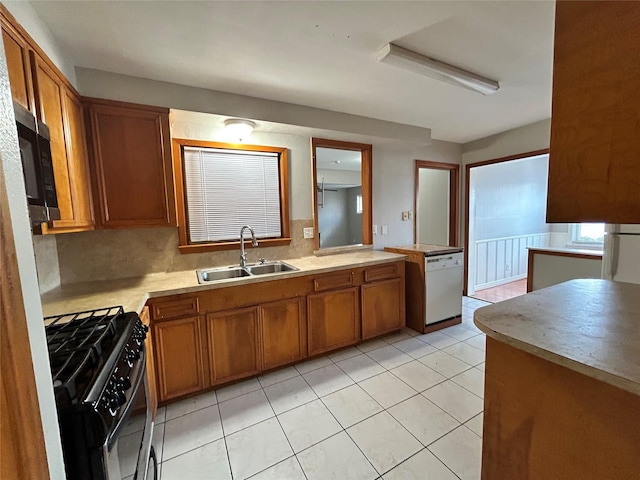 kitchen featuring dishwasher, sink, light tile patterned flooring, and black range with gas cooktop