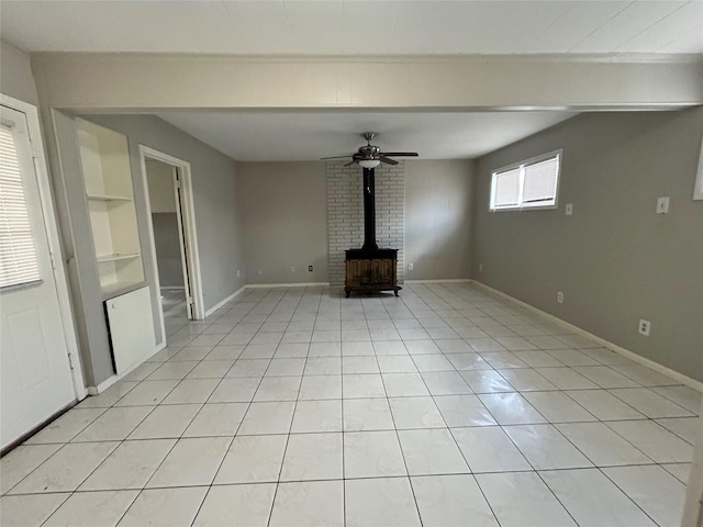 unfurnished living room featuring light tile patterned floors, built in shelves, ceiling fan, and a wood stove