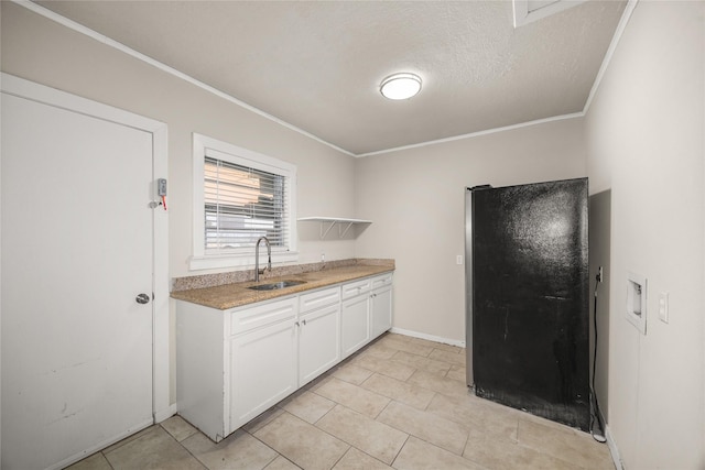 kitchen featuring sink, a textured ceiling, black refrigerator, ornamental molding, and white cabinets