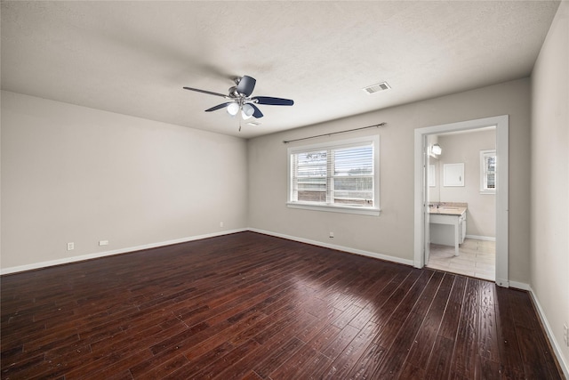 interior space featuring ceiling fan, wood-type flooring, a textured ceiling, and ensuite bathroom