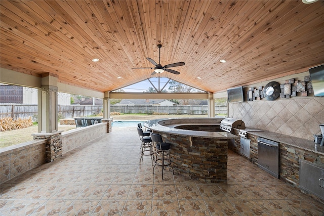 view of patio featuring area for grilling, ceiling fan, and a bar