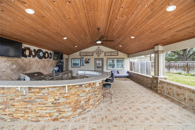 view of patio / terrace featuring a bar, a grill, ceiling fan, and exterior kitchen