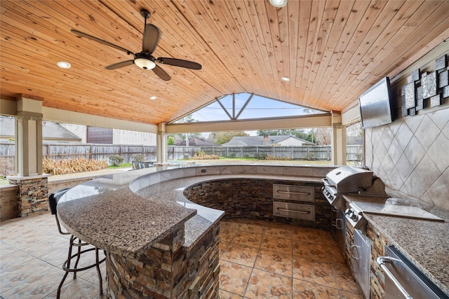 view of patio with a bar, an outdoor kitchen, a grill, ceiling fan, and a gazebo